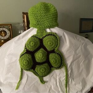 Bundle up baby in handmade turtle costume of knit hat attached to tortoise shell